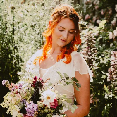 A bride with red hair holding a bouquet of flowers.